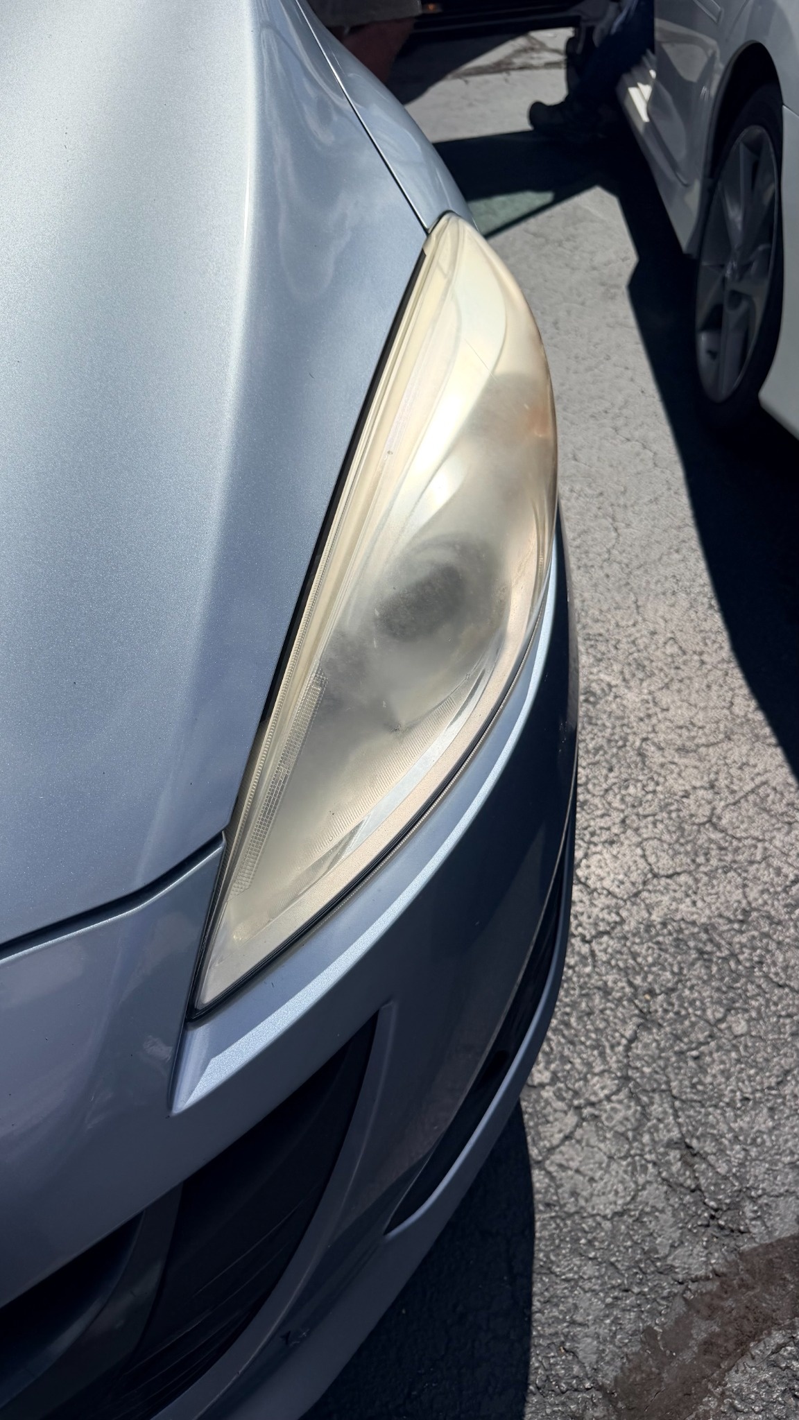 Before headlight restoration showing cloudy, hazy lens on a silver vehicle